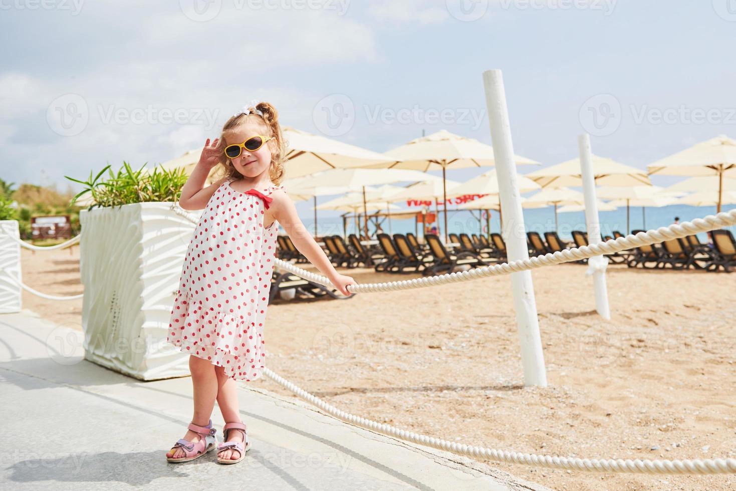 glad flicka i en klänning på stranden vid havet på sommaren. foto