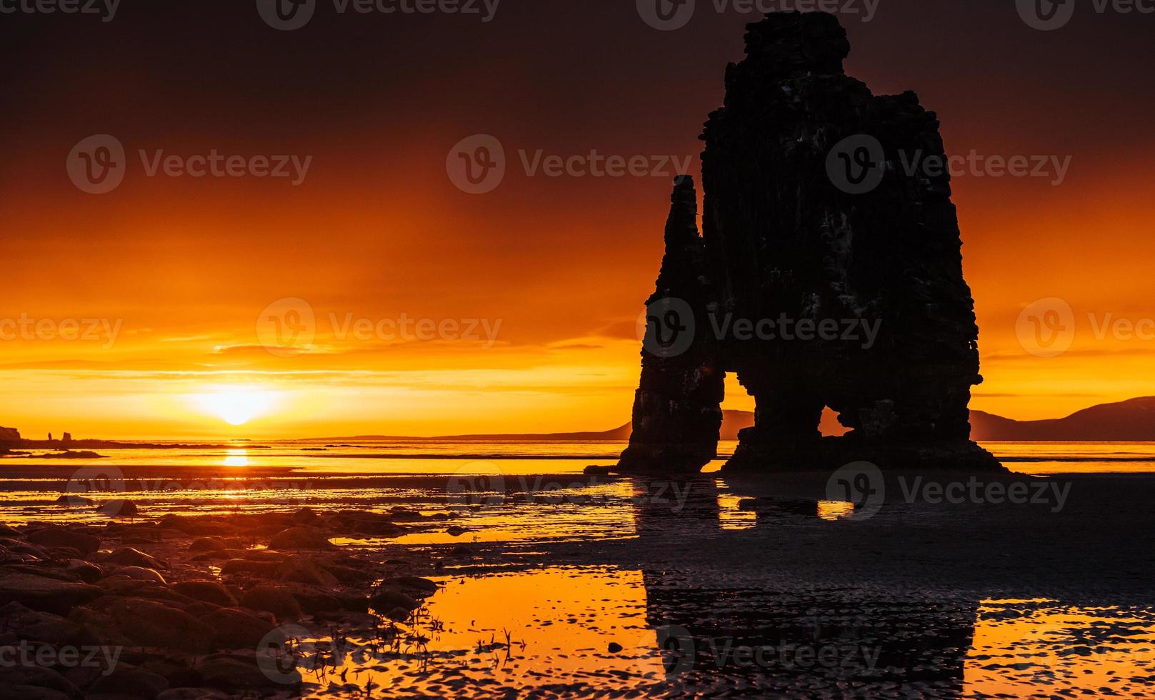 är en spektakulär sten i havet på islands norra kust. legender säger att det är ett förstenat troll. på denna bild reflekterar hvitserkur i havsvattnet efter midnattssolnedgången. foto