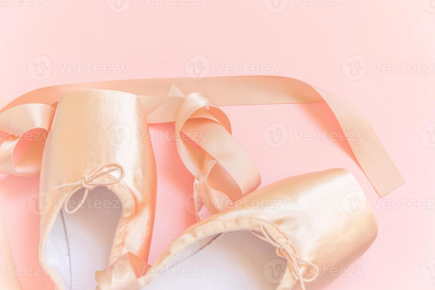 nya pastellbeige balettskor med satinband isolerad på rosa bakgrund. ballerina klassiska pointe skor för dansträning. balettskola koncept. ovanifrån platt låg, kopiera utrymme foto