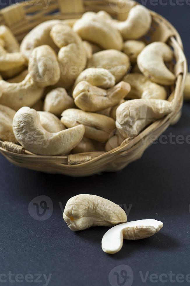 cashewnötter i korg på svart bakgrund foto