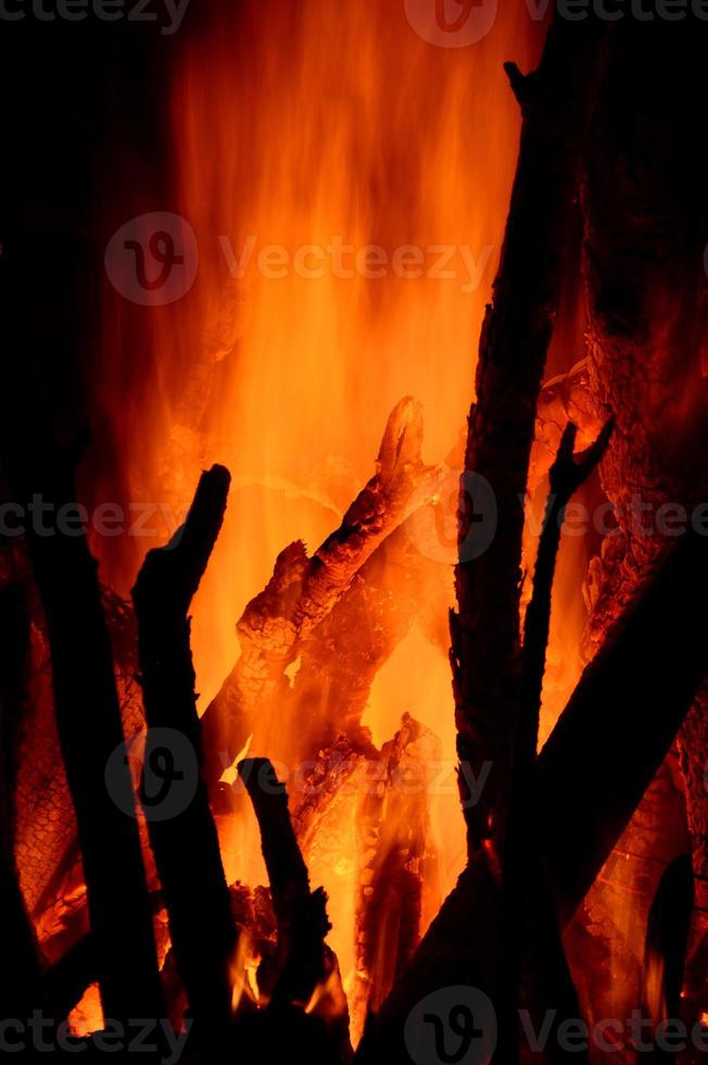 närbild av brinnande stockar i spisen på svart bakgrund foto