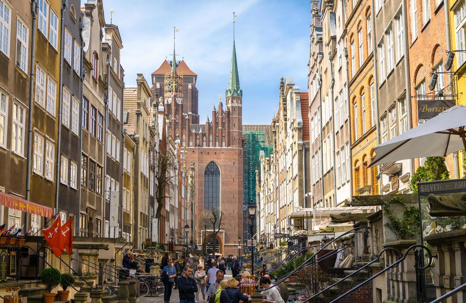 gdansk, Polen, 15 april 2018 människor går längs mariackagatan med typiska färgglada hus byggnader och basilikan antagande välsignade jungfru St Marys kyrka katedral i gamla historiska centrum foto