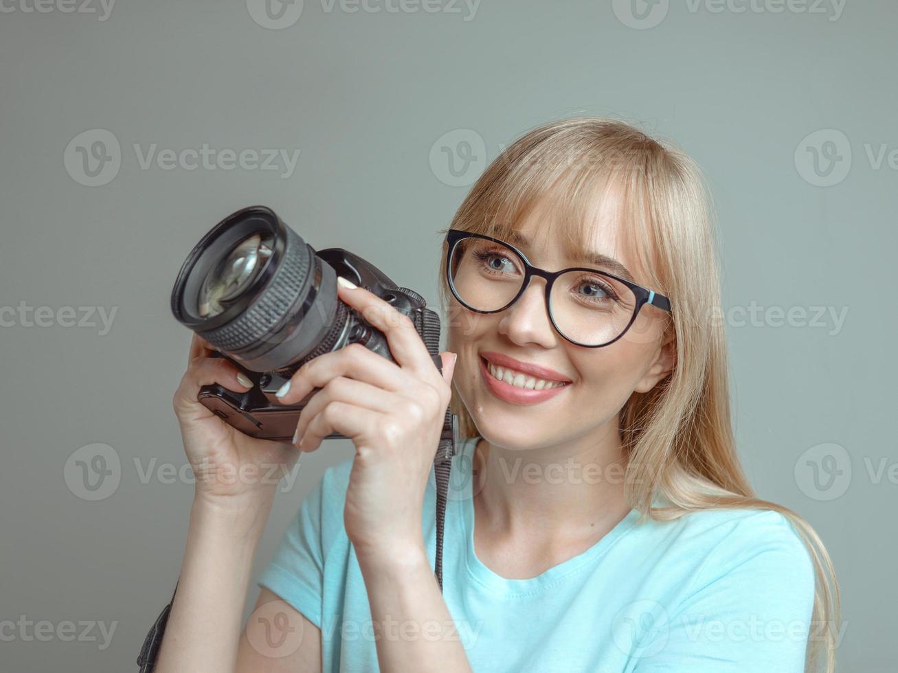 blond snygg glad kvinna fotograf i glasögon och hålla fotokamera. hobby, arbete, skytte koncept foto