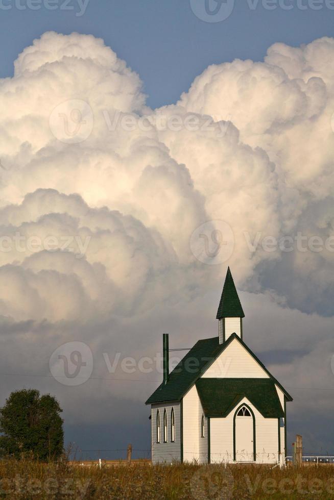 åska moln bildas bakom en landskyrka foto