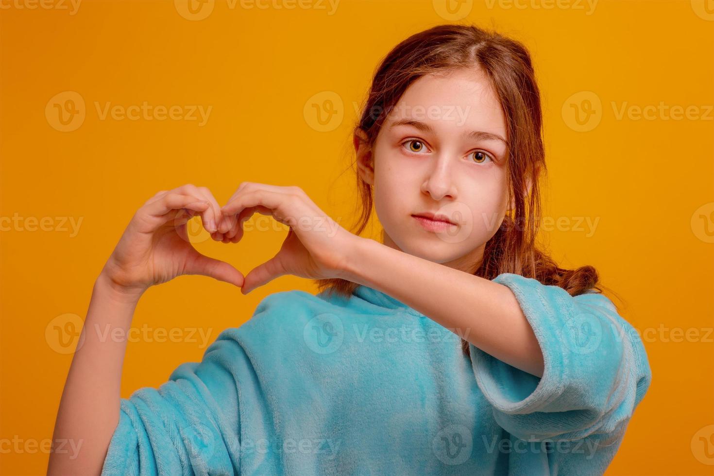 flicka för fred, sluta kriget. flicka i en blå hoodie på en gul bakgrund visar sina händer till hjärtat. foto