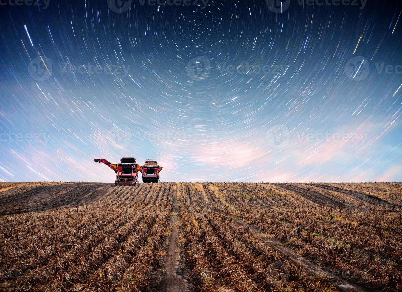 traktor plöjning gårdsfält som förberedelse för vårplantering. fantastisk stjärnhimmel och Vintergatan foto