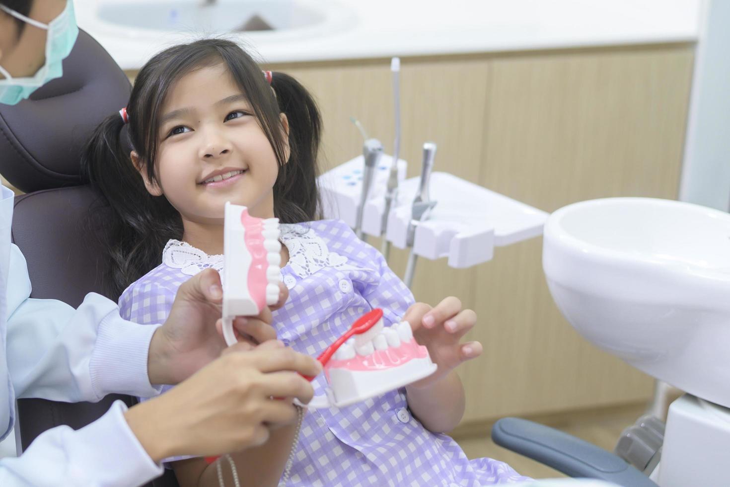 en liten söt flicka som har tänder undersökta av tandläkare på tandklinik, tandkontroll och friska tänder koncept foto