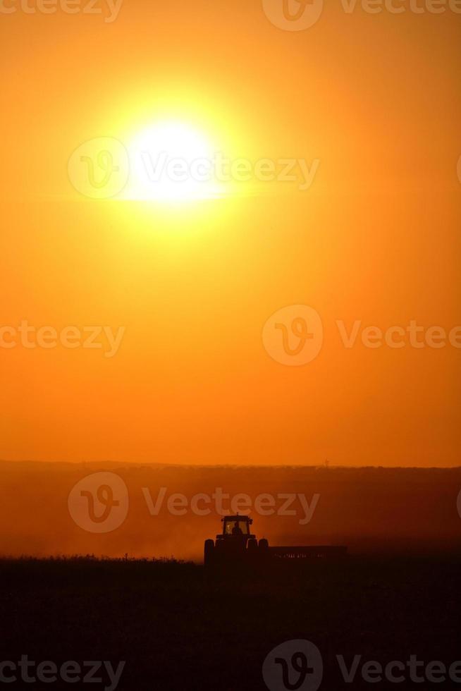 solnedgången bakom jordbruket arbetar hans fält foto