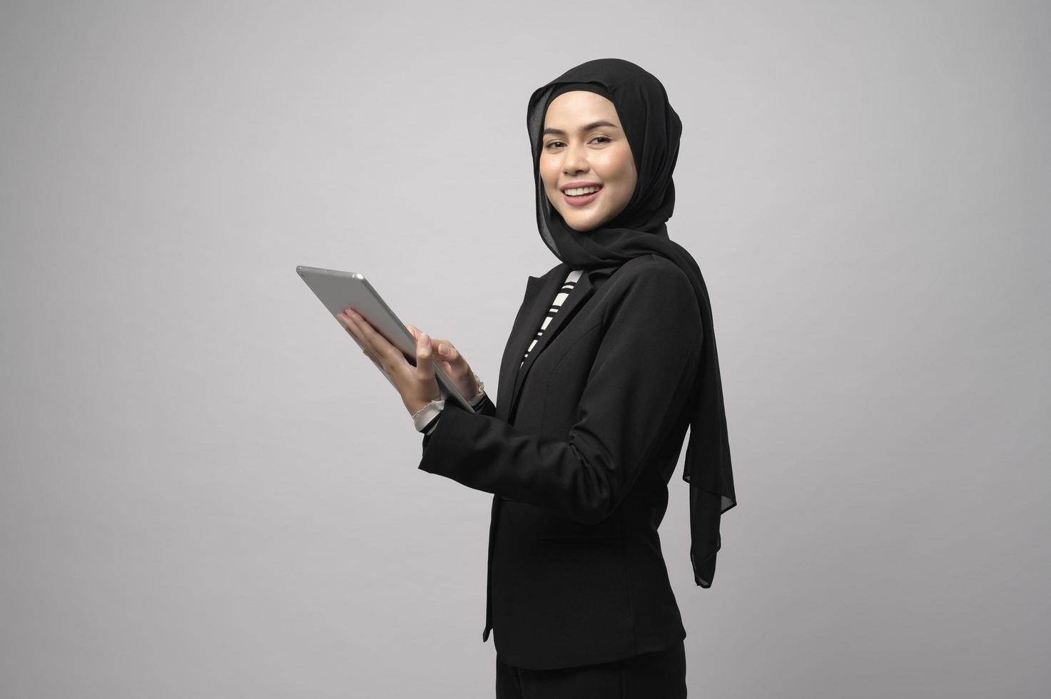 porträtt av ung vacker muslimsk affärskvinna håller tablett över vit bakgrund studio foto