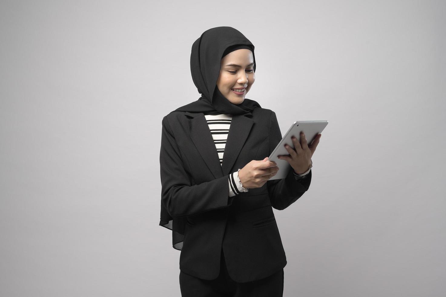 porträtt av ung vacker muslimsk affärskvinna håller tablett över vit bakgrund studio foto
