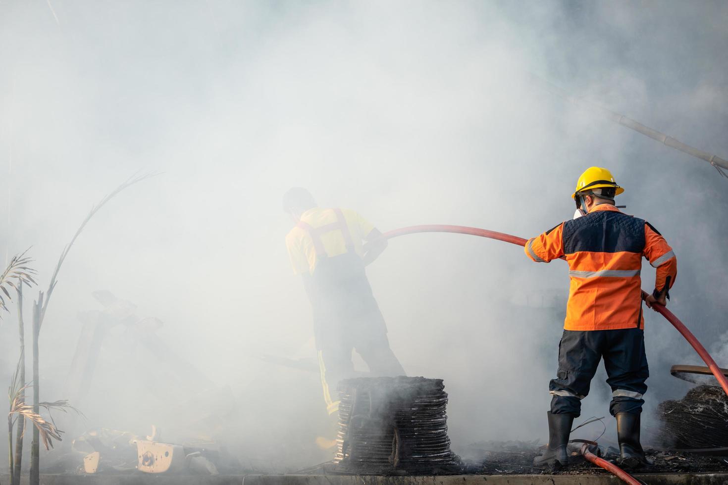 brandman sprutar vatten från en stor vattenslang för att förhindra brand foto