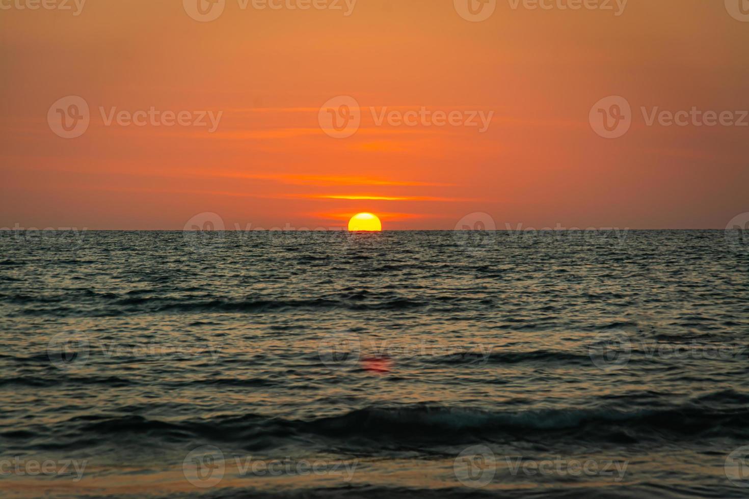 ljus solnedgång med stor gul sol under havsytan foto