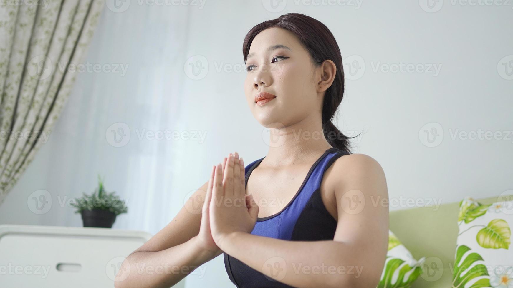 asiatisk kvinna yoga hemma gör handövningar med fokus foto