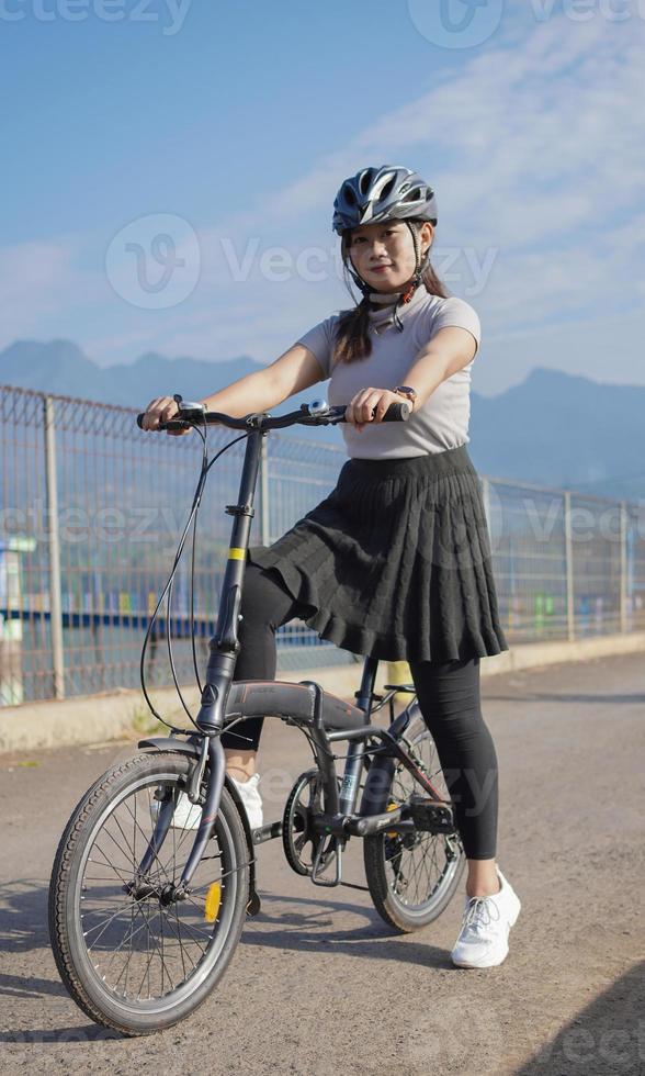 ung asiatisk kvinna njuter av att cykla när den stannade på sommarmorgonen foto