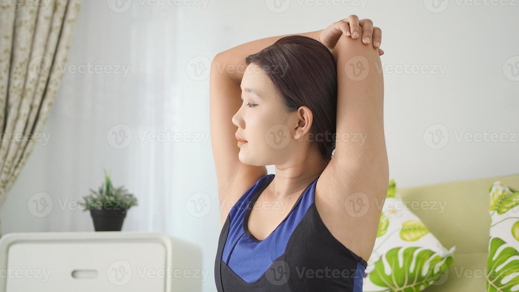 asiatisk kvinna utövar yoga gör handvärma upp hemma foto