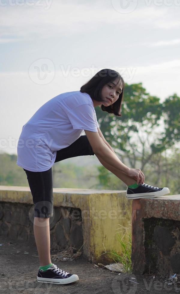 ung asiatisk kvinna har förbereda sina skor innan hon springer och joggar på morgonen foto