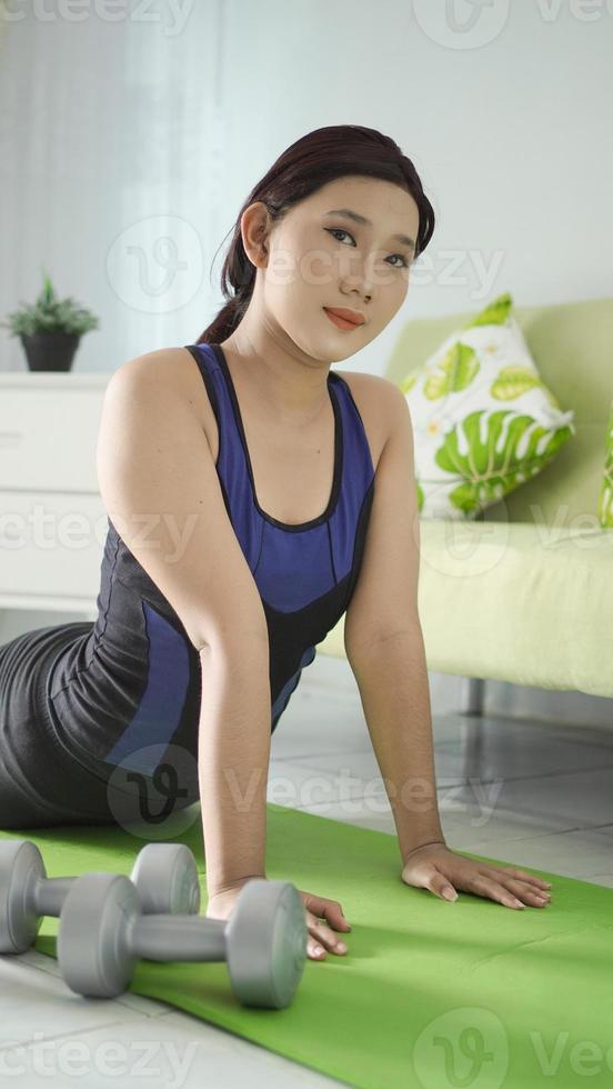 asiatisk kvinna som utövar yoga hemma gör flexibilitetsuppvärmning foto