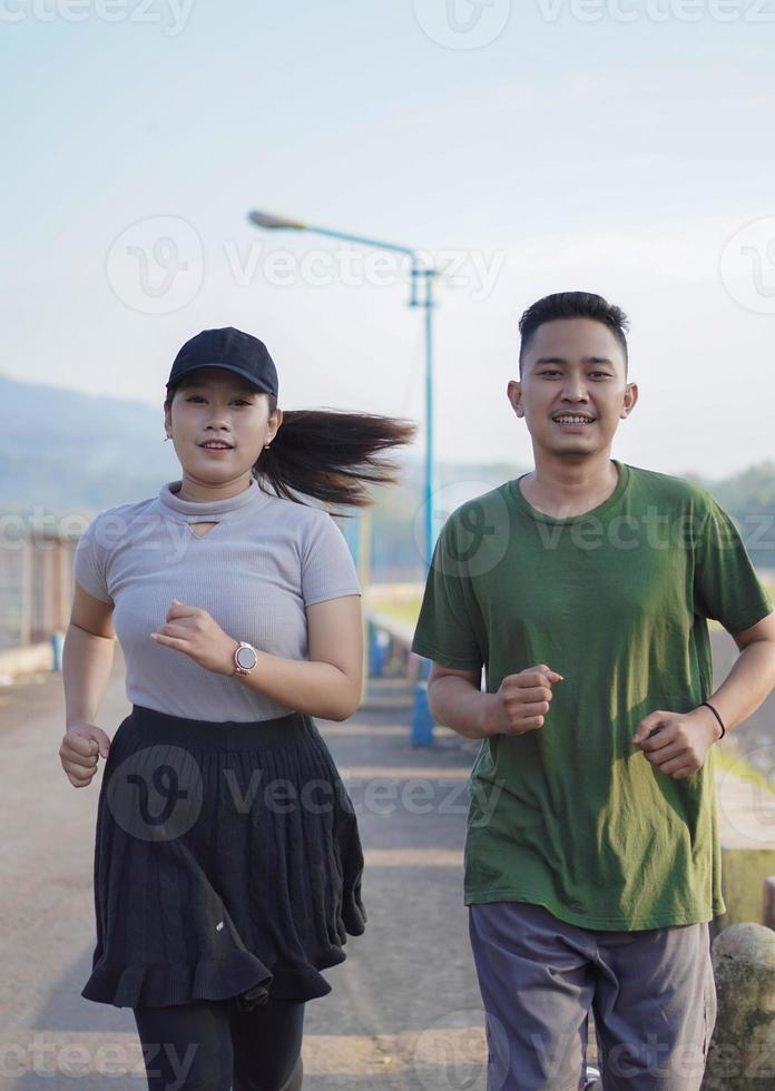 unga asiatiska par i sportiga kläder kör tillsammans på morgonen foto