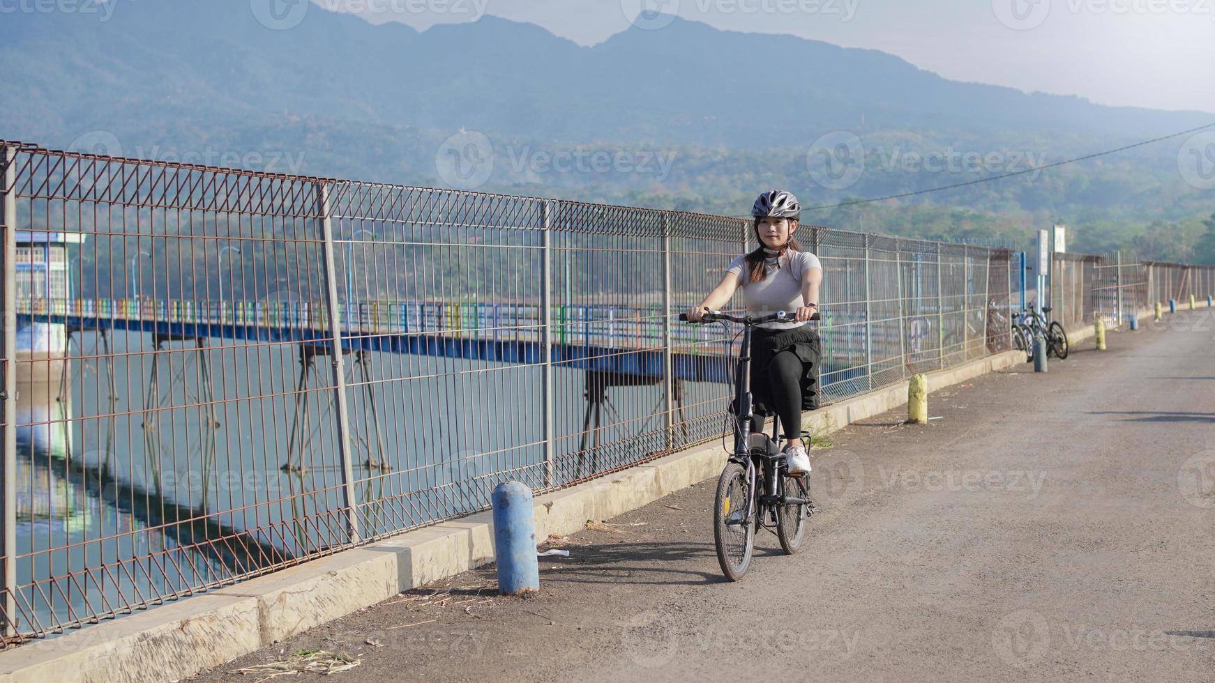 ung asiatisk kvinna cyklar på sommaren foto