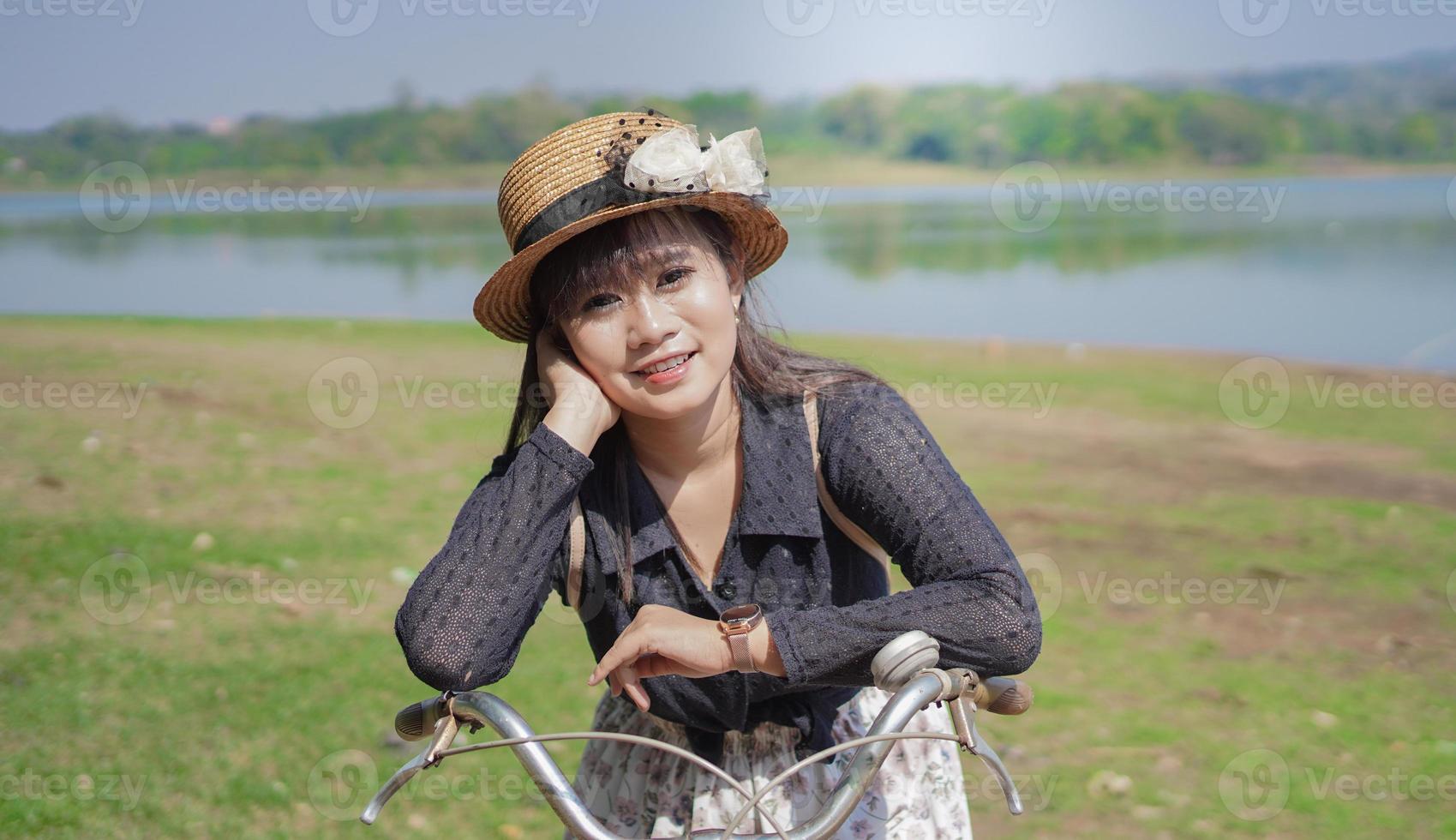 ung asiatisk kvinna njuter av att cykla medan hon stannar vid parken foto