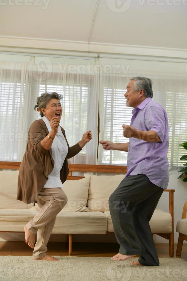 spenderar tid tillsammans hemma, ett äldre asiatiskt par som har roligt när de dansar i vardagsrummet. foto