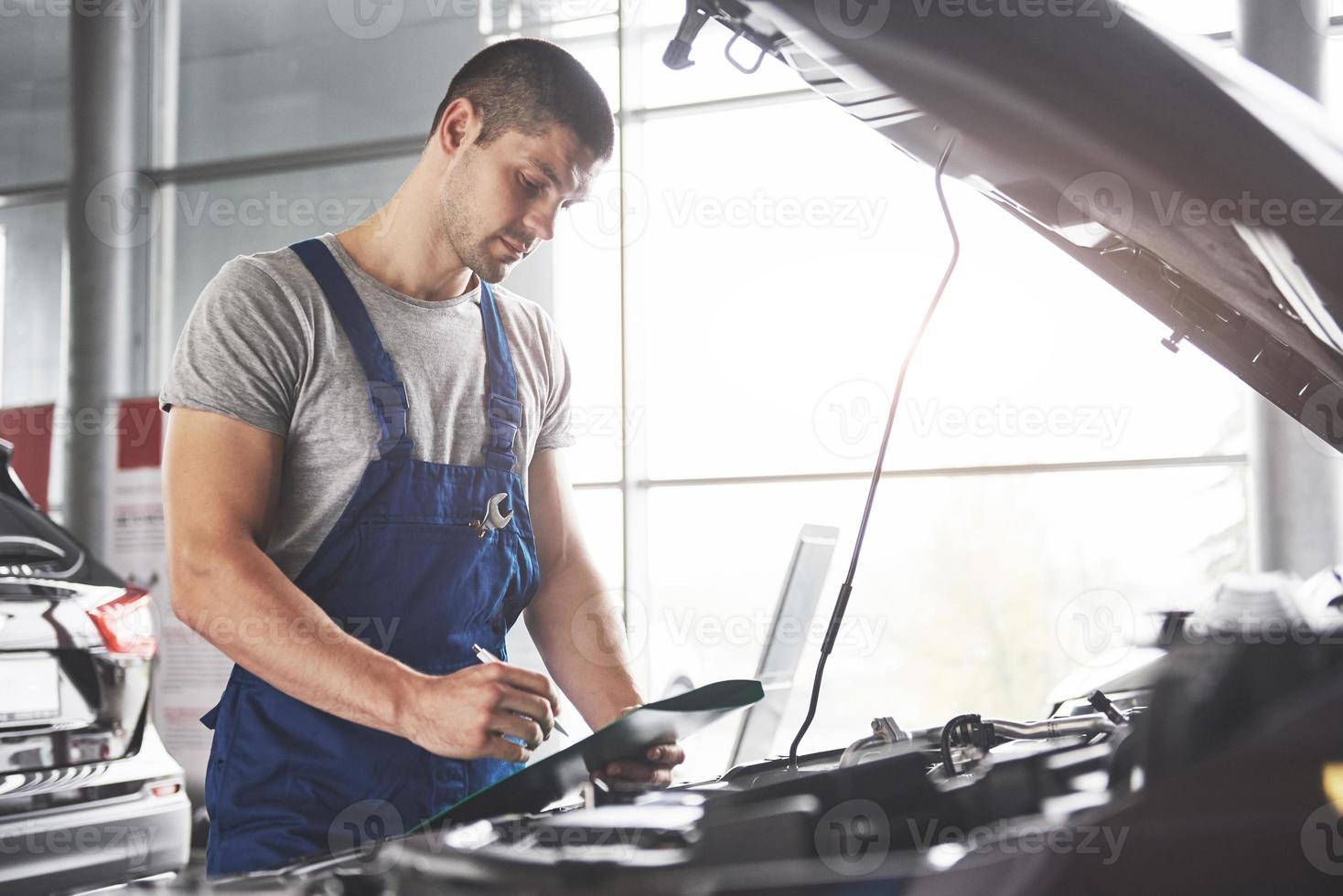 porträtt av en mekaniker på jobbet i hans garage - bilservice, reparation, underhåll och människor koncept foto