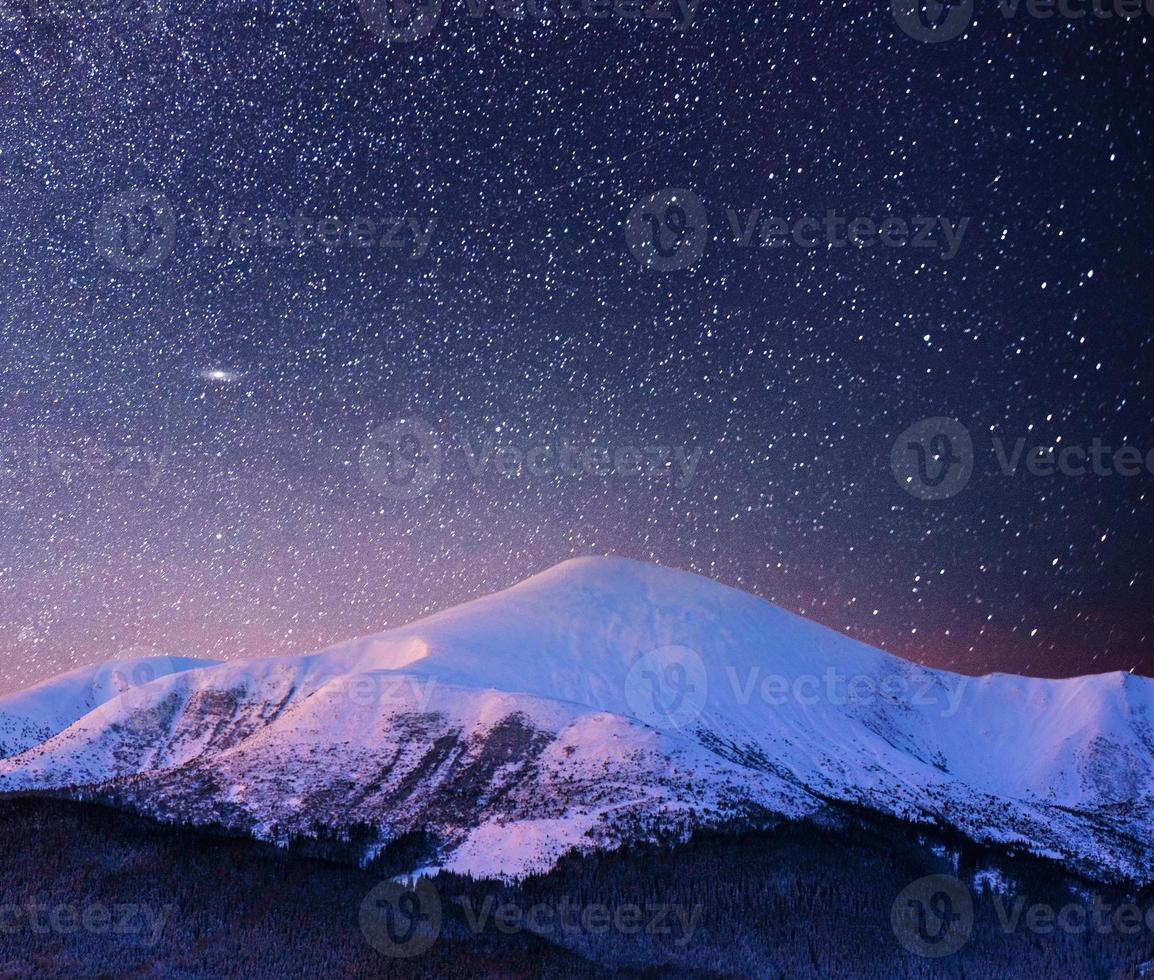 vackert vinterlandskap i Karpaterna. pulserande natthimmel med stjärnor och nebulosa och galax. deep sky astrofoto foto