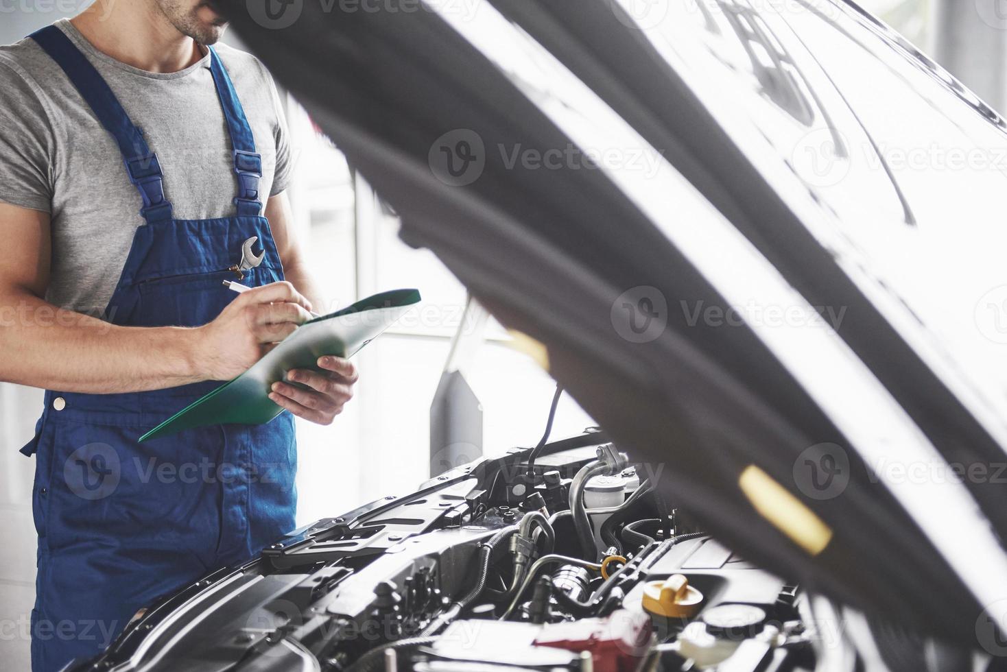 porträtt av en mekaniker på jobbet i hans garage - bilservice, reparation, underhåll och människor koncept foto