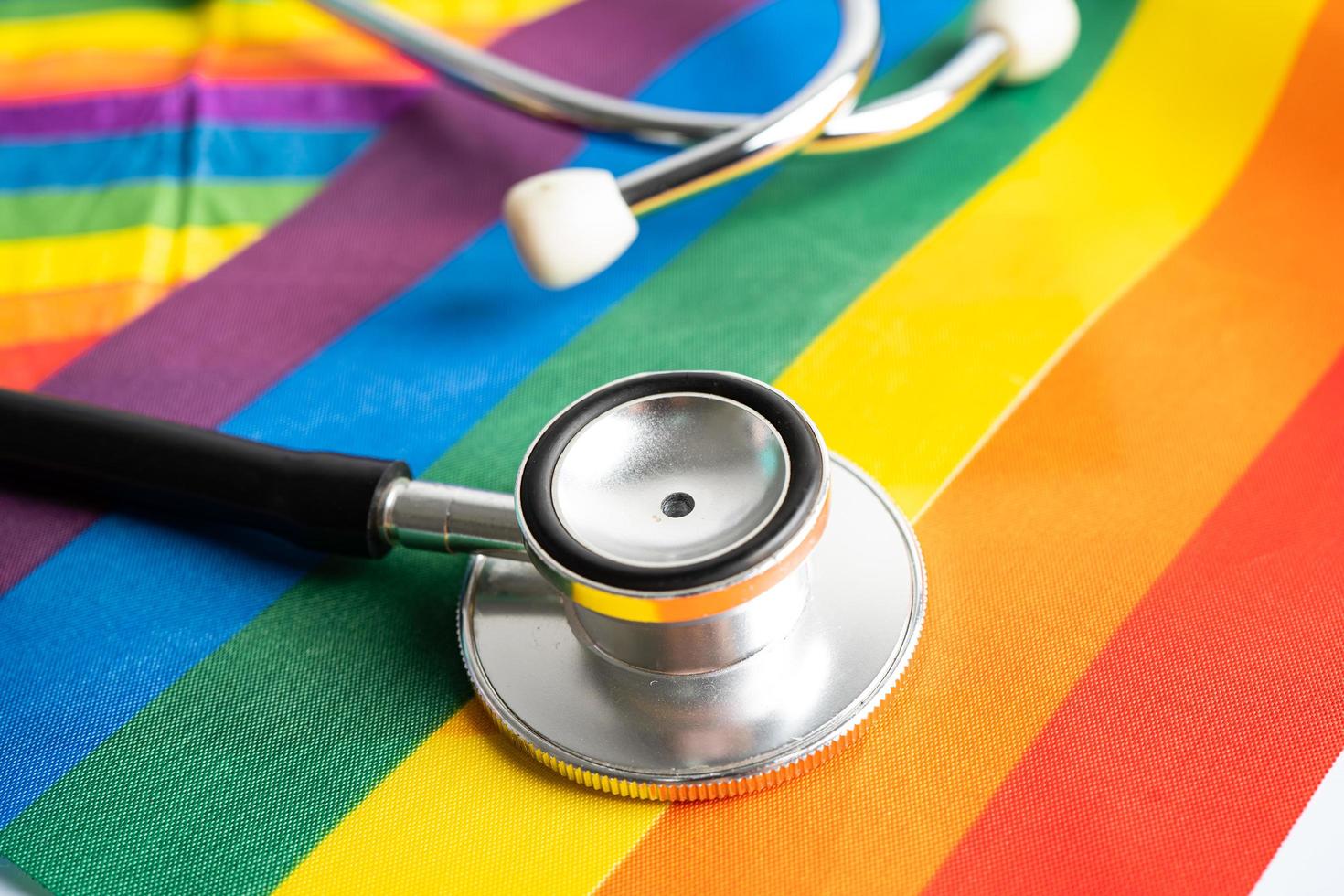 svart stetoskop på regnbågsflagga bakgrund, symbol för lgbt pride månad fira årliga i juni social, symbol för homosexuella, lesbiska, bisexuella, transpersoner, mänskliga rättigheter och fred. foto