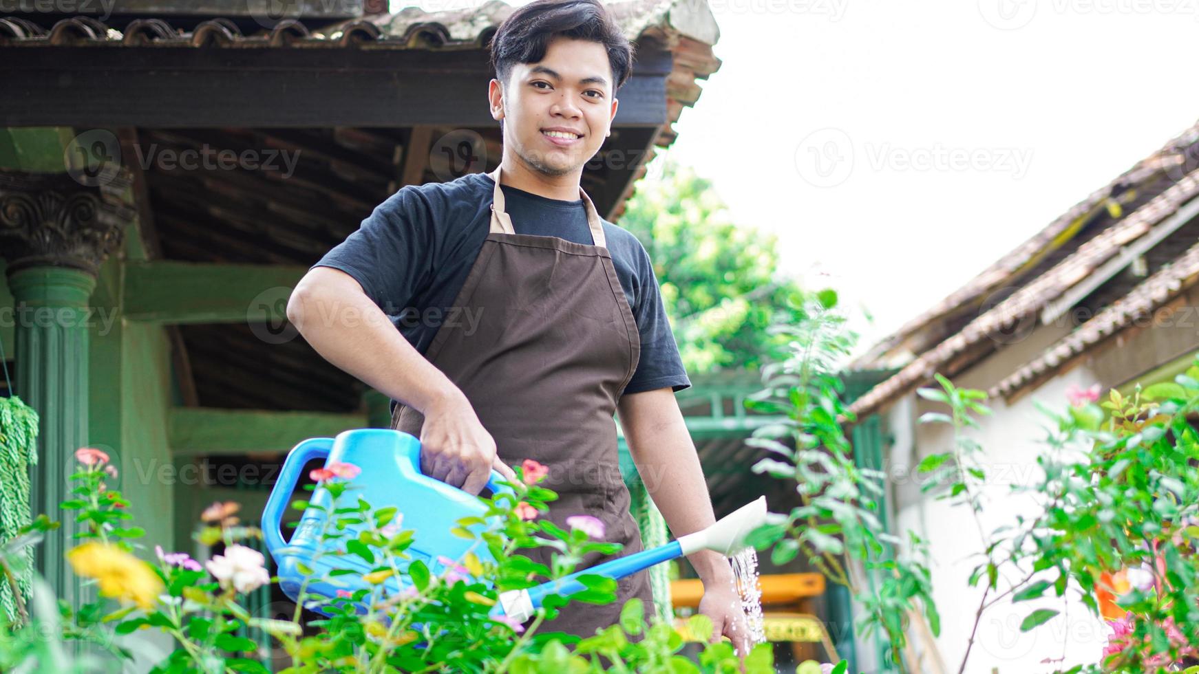 asiatisk man tar hand vattning blomma hemma trädgård foto