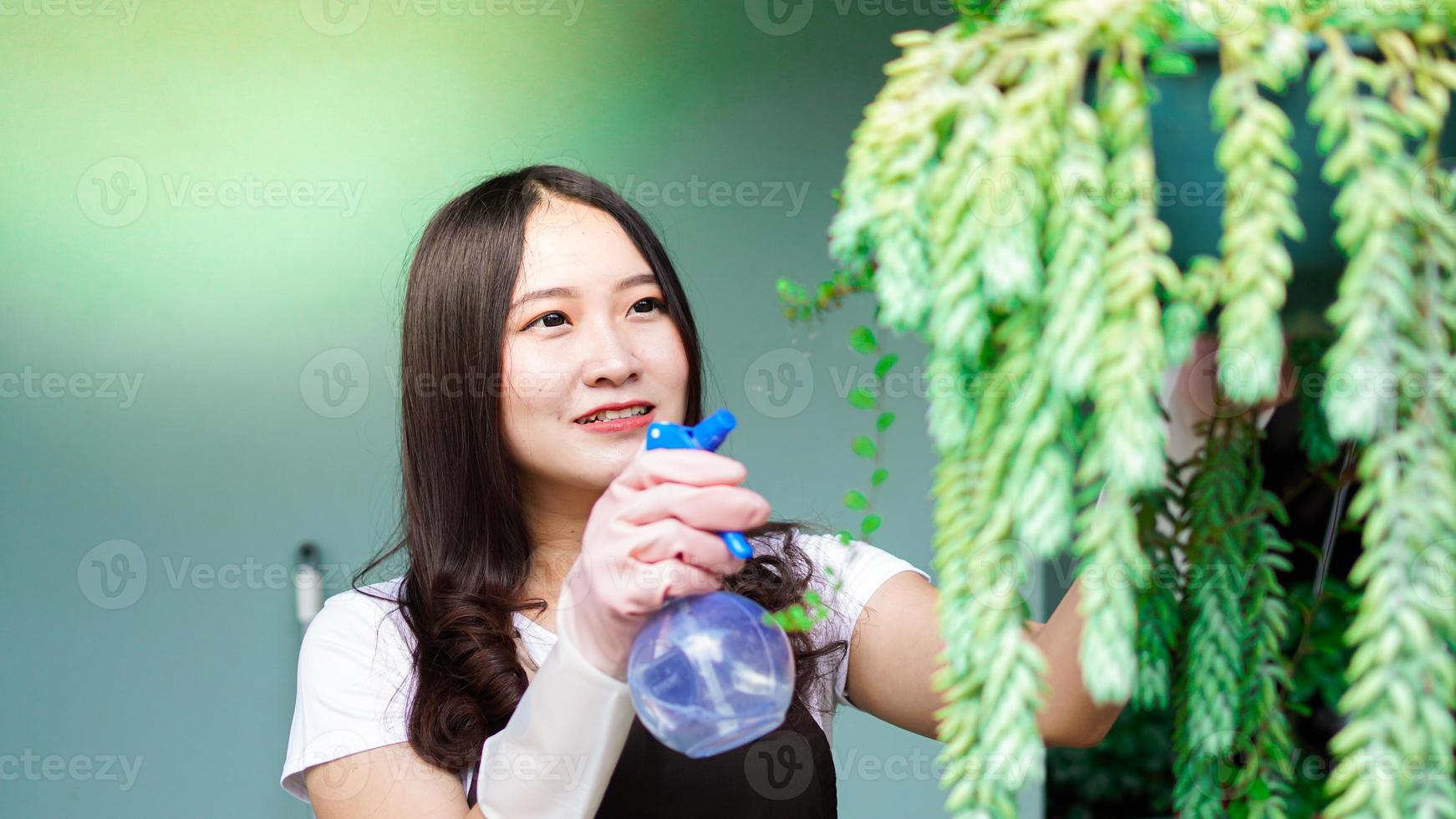 asiatisk kvinna tar hand vattning blomma hemma trädgård foto