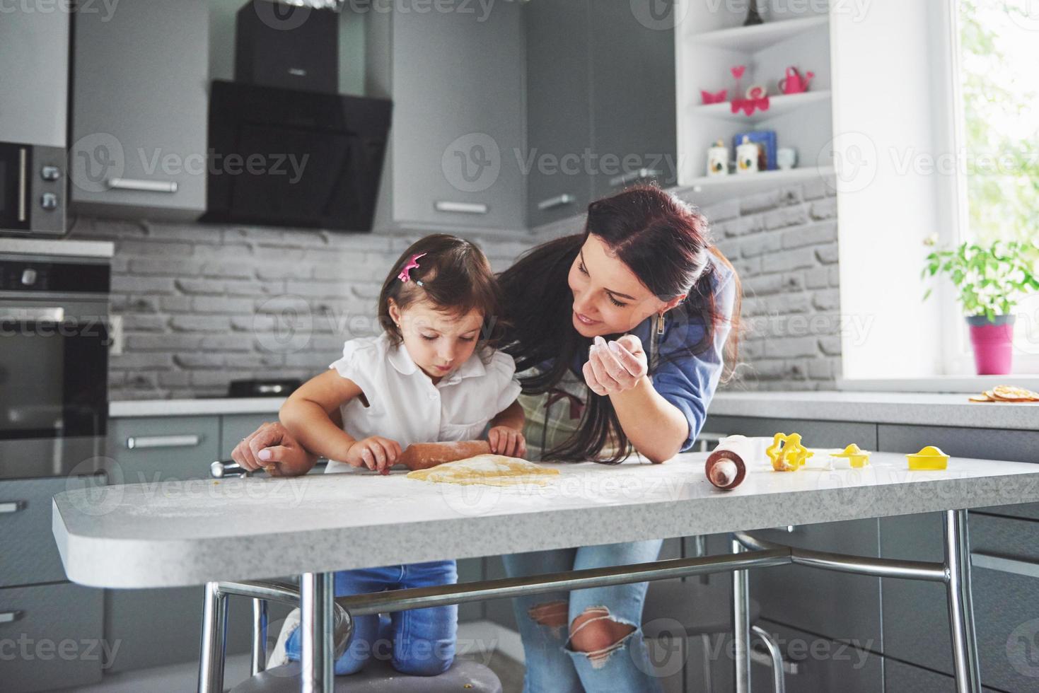 lycklig familj i köket. semester mat koncept. mor och dotter förbereder degen, bakar kakor. lycklig familj i att göra kakor hemma. hemlagad mat och liten hjälpreda foto