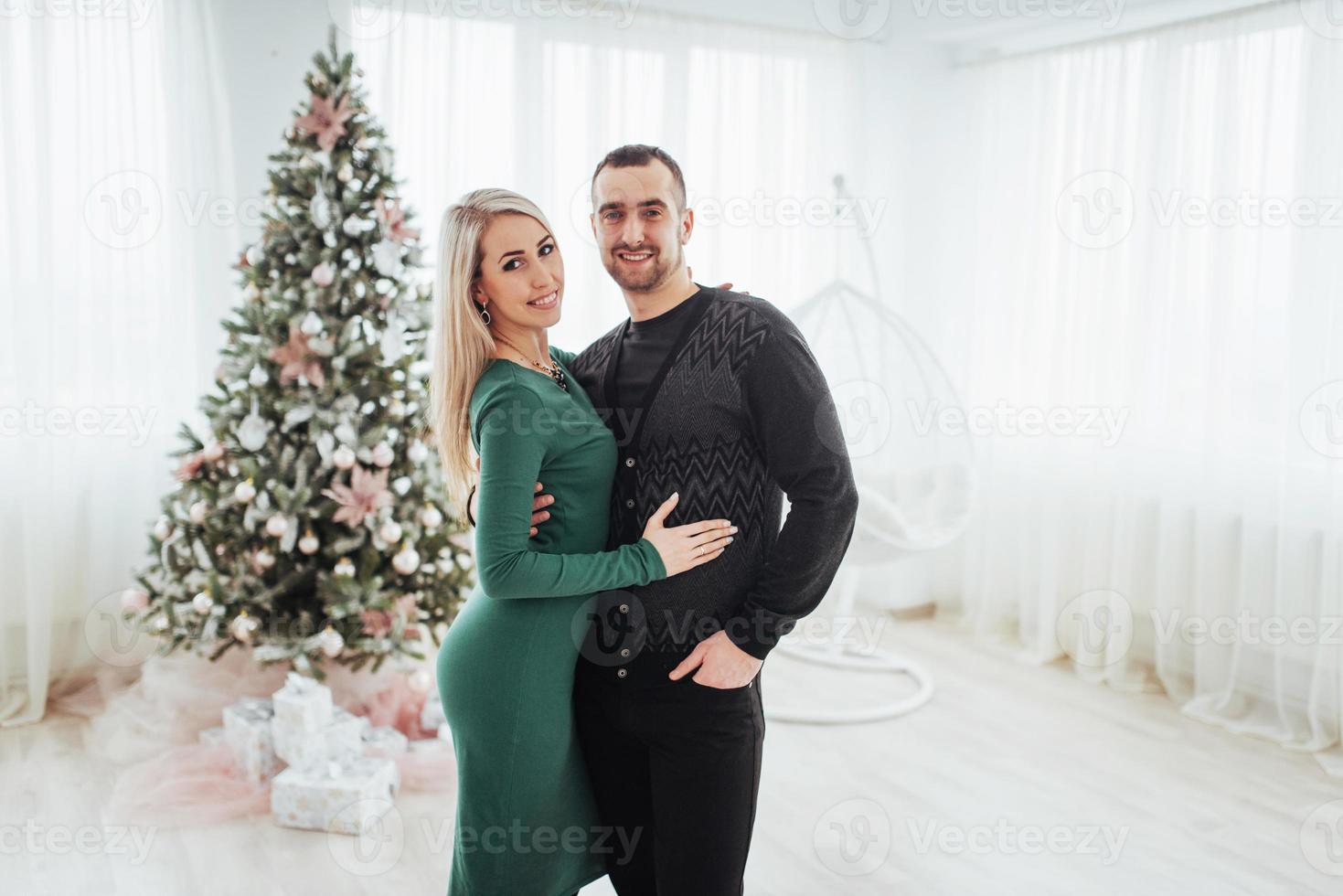 lyckligt ungt par vid jul, vackra presenter och träd i bakgrunden foto