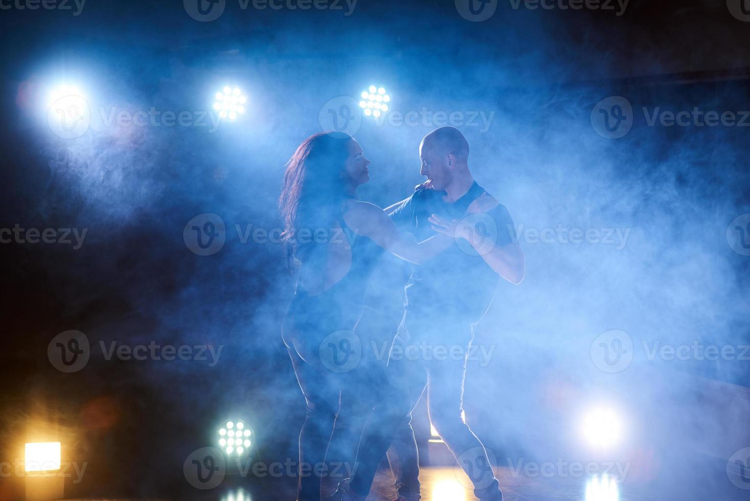 skickliga dansare som uppträder i det mörka rummet under konsertens ljus och rök. sensuellt par som utför en konstnärlig och känslomässig samtida dans foto