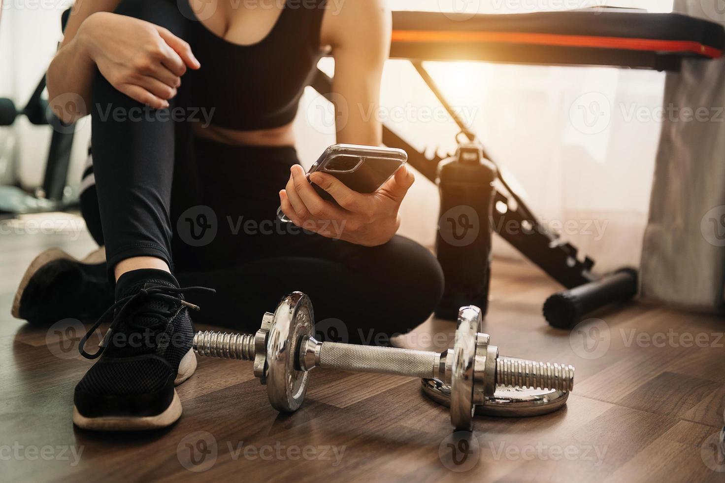 närbild av kvinna som använder smart telefon medan du tränar i gymmet. sport och teknik koncept. livsstil och hälsotema. foto