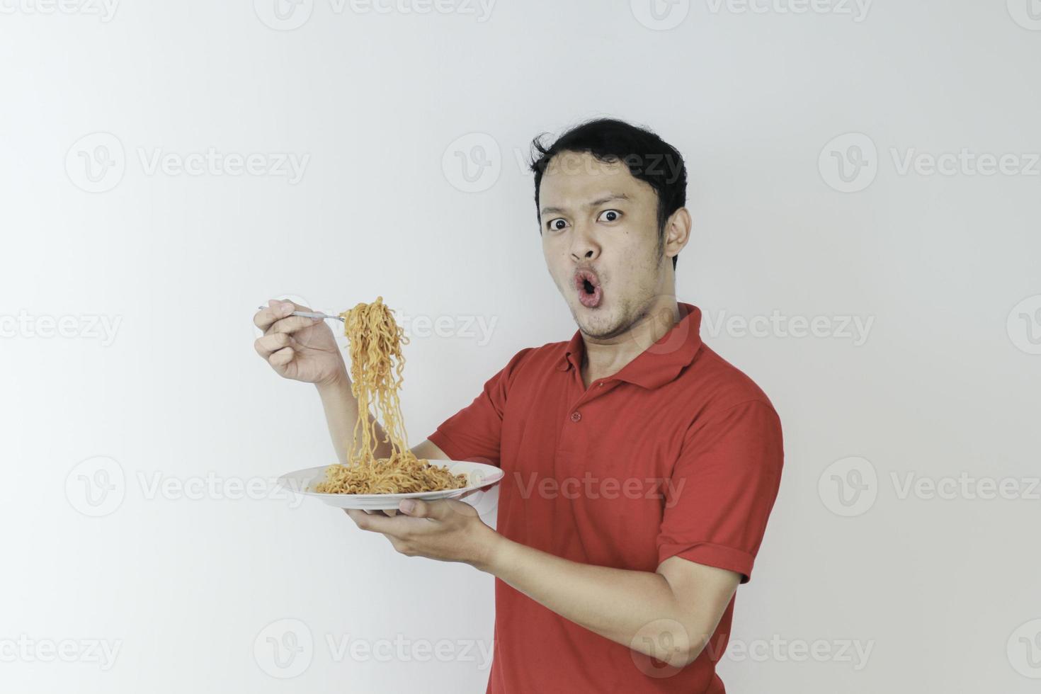 porträtt av chock och wow ung asiatisk man njuta av nudlar. äta lunch koncept foto