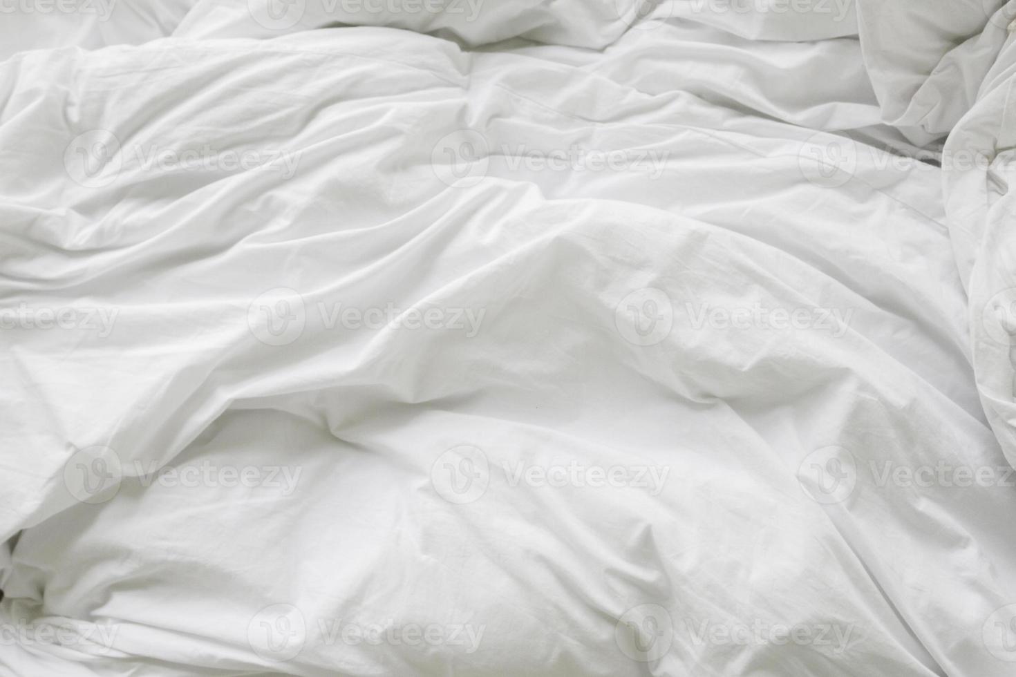 skrynkla rörig filt och vit kudde i sovrummet efter att ha vaknat på morgonen, från att sova en lång natt. foto