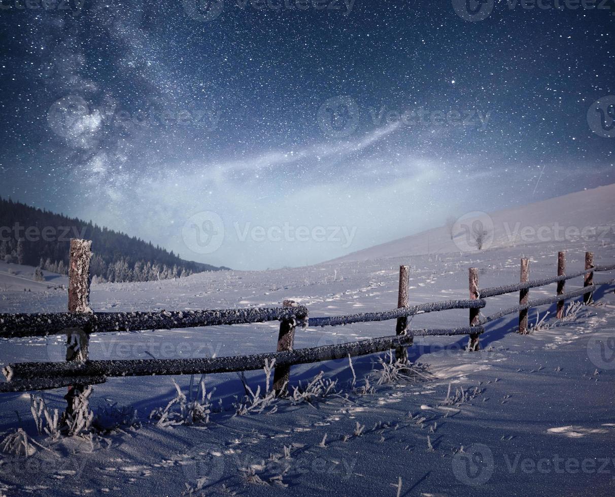 vinterlandskap. bergsby i de ukrainska karpaterna. pulserande natthimmel med stjärnor och nebulosa och galax. deep sky astrofoto foto