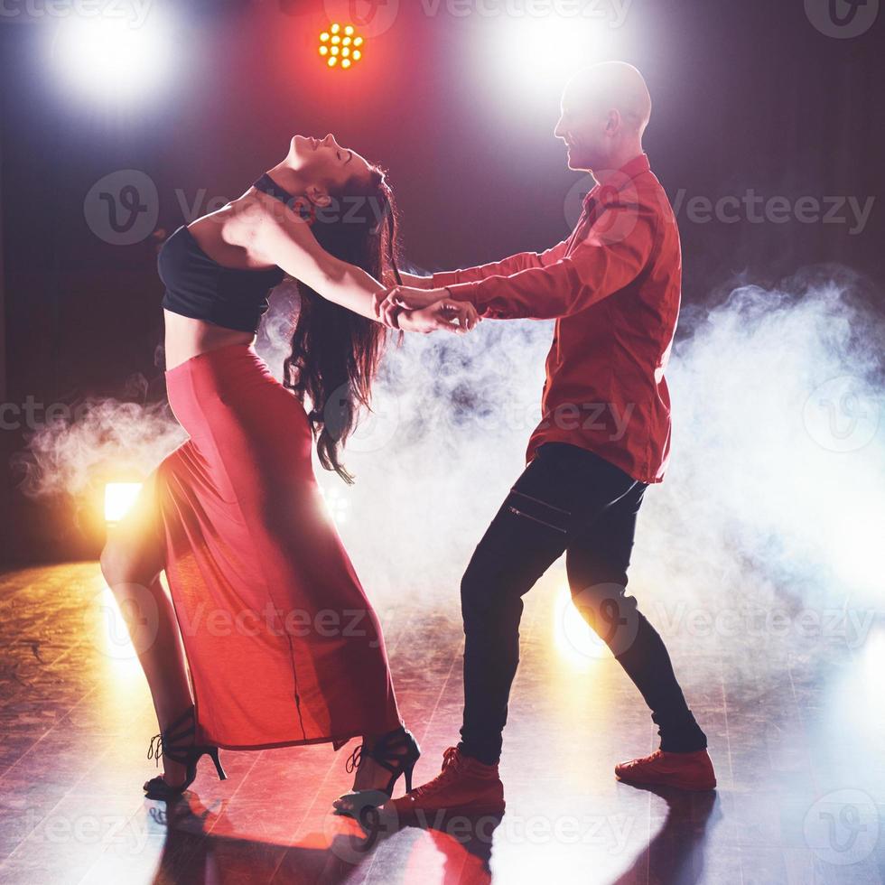 skickliga dansare som uppträder i det mörka rummet under konsertens ljus och rök. sensuellt par som utför en konstnärlig och känslomässig samtida dans foto