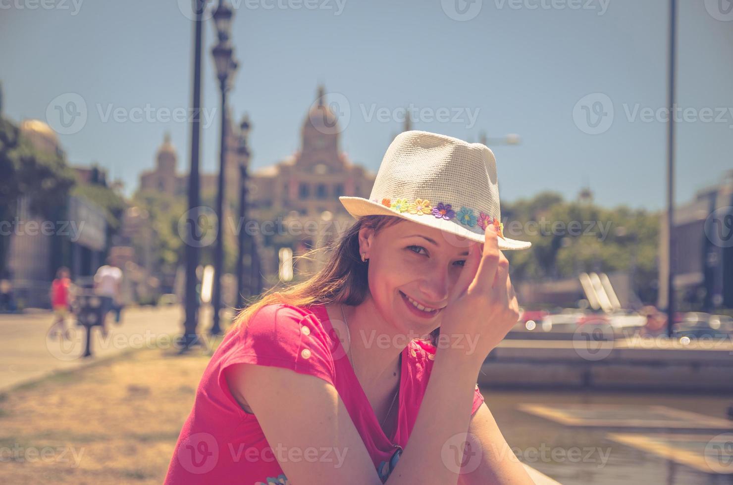 ung vacker kvinna resenär med röd klänning och hatt poserar i Barcelona stad i solig sommardag foto