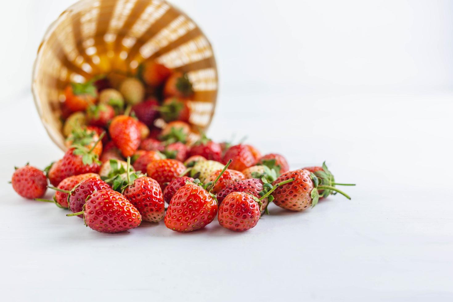 färska jordgubbar i en korg på en vit bakgrund foto