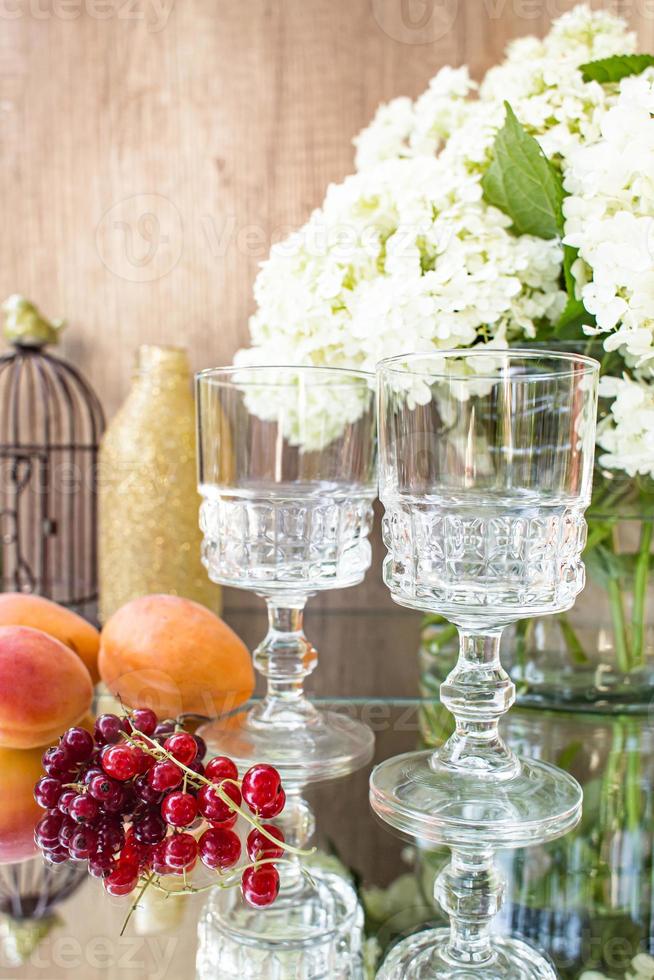 rosévin i glas. rosa vin på gyllene flaskor bakgrund med blommor och frukter foto