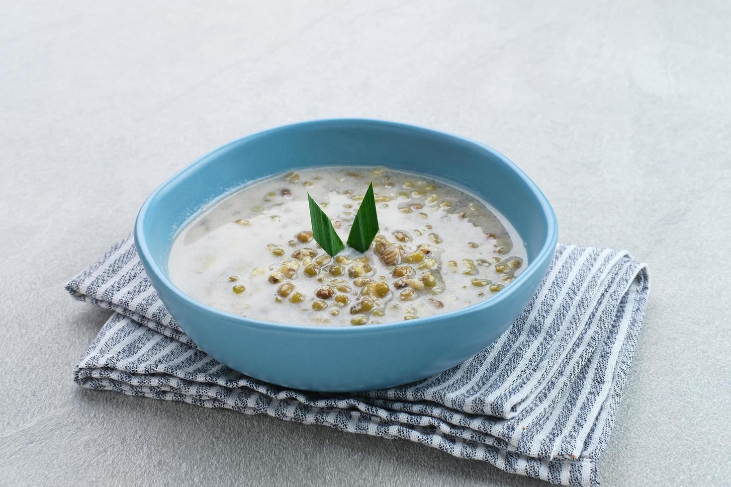 mungbönsgröt eller bubur kacang hijau, indonesisk dessertgröt av mungbönor med kokosmjölk, pandanblad och ingefära. serveras i skål. foto