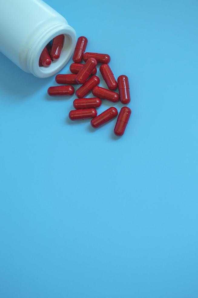 medicinsk koncept rör med piller, kapslar av röd färg på blå bakgrund. läkemedel mot covid19 eller vitaminer för immunitet. återhämtning från covid 19. kosttillskott. foto