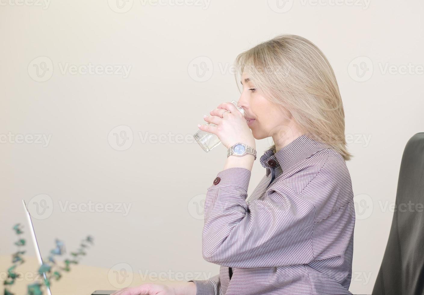 törstig kvinna på kontoret dricksvatten under arbetsdagen. huden fuktgivande och fuktgivande. kontorsarbete. blond anställd kvinna., kopia utrymme foto