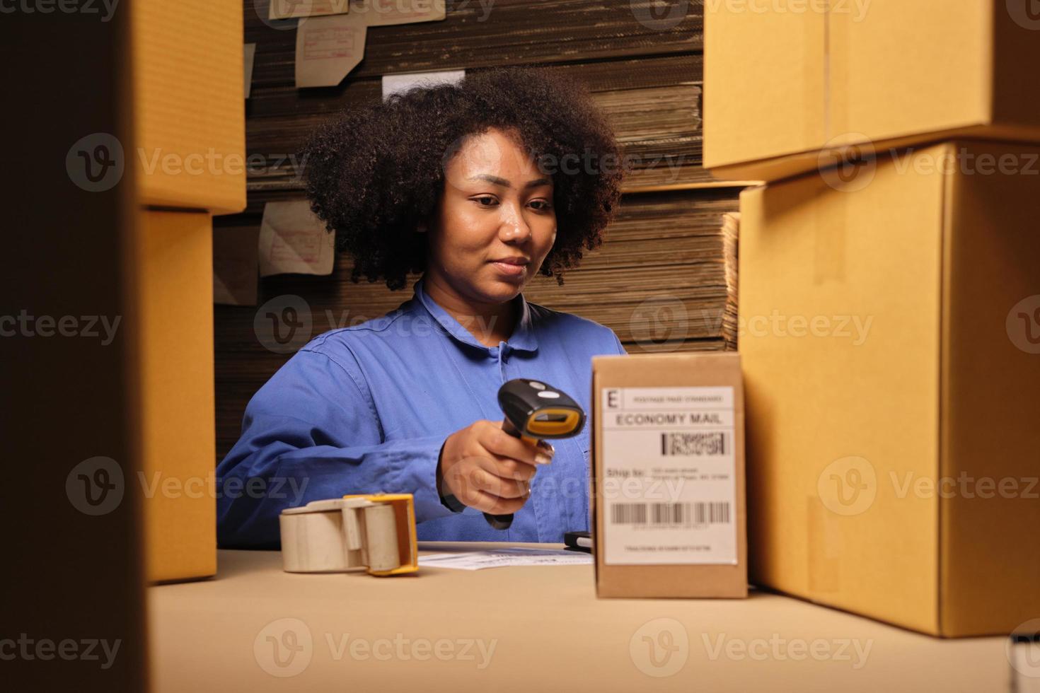 afrikansk amerikansk kvinnlig arbetare i säkerhetsuniform som använder streckkodsläsare för att kontrollera leveransordrar på paketlager, papperstillverkningsfabrik för förpackningsindustrin, logistisk transporttjänst. foto