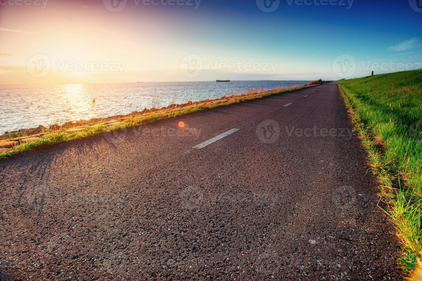 asfaltväg längs havet vid solnedgången foto