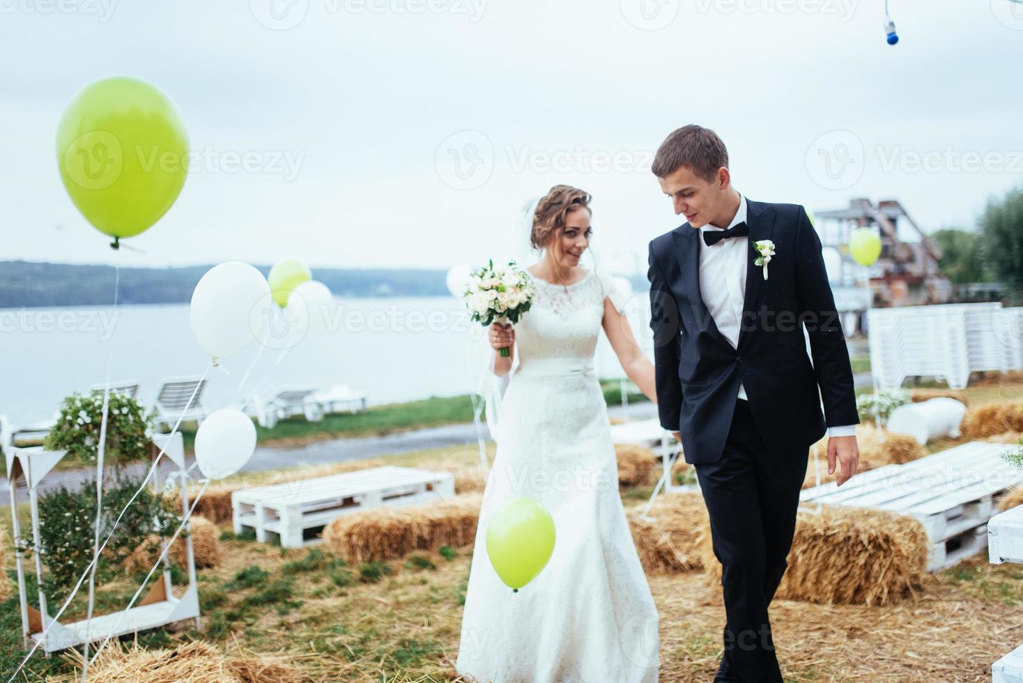 vackra unga bröllopsparet kysser, blond brud med flowe foto