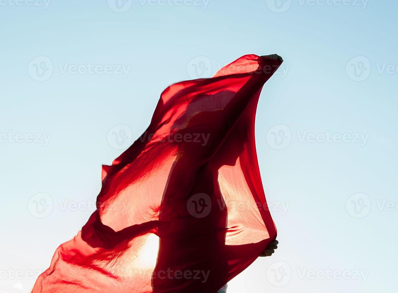 kvinna insvept i en röd halsduk i vinden foto