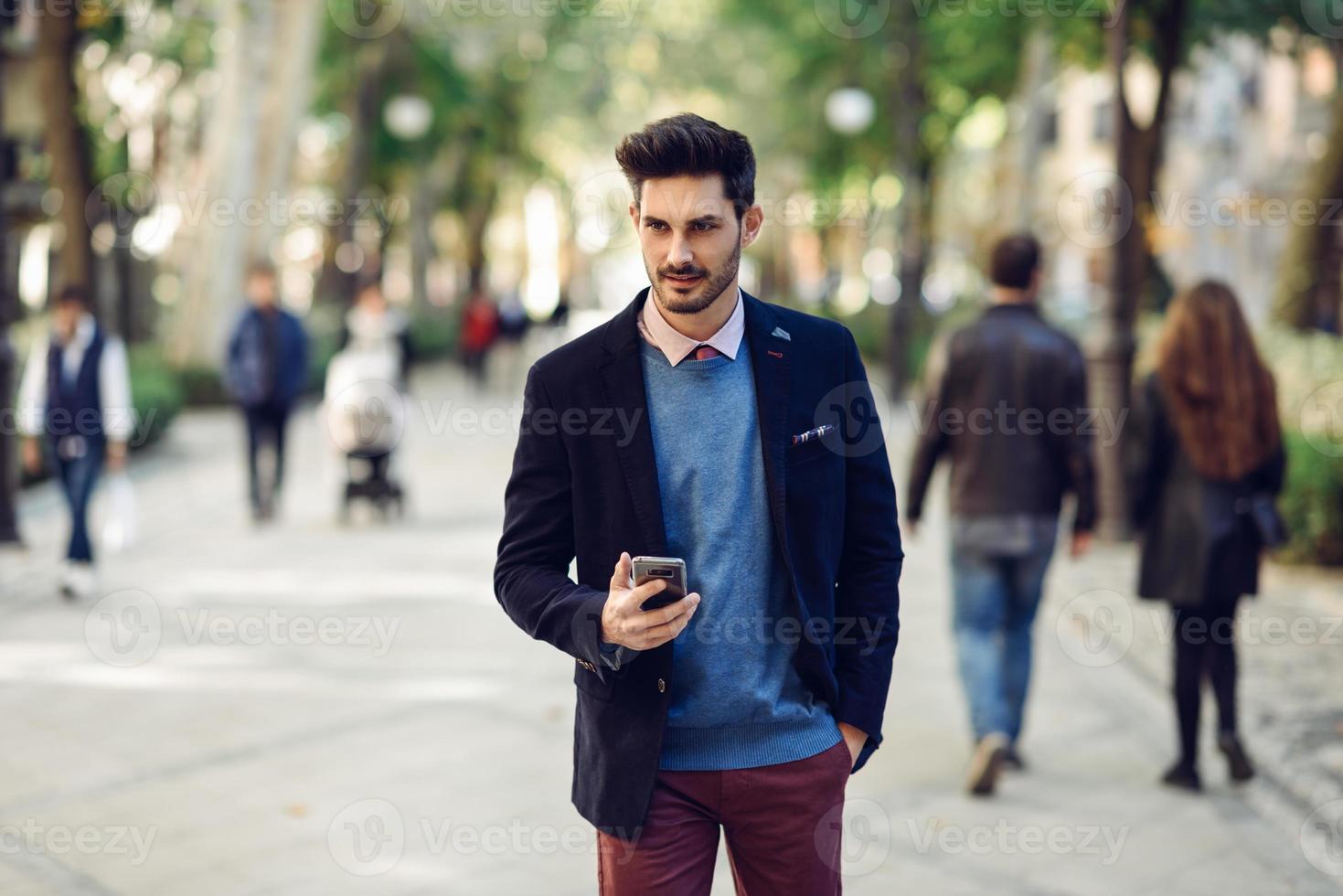 man på gatan i formella kläder med smartphone i handen. foto